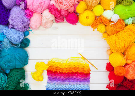 Kugeln aus farbigen Garnen. Blick von oben. alle Farben des Regenbogens. Probe gestrickt. Frauenhände gestrickt sind. häkeln. Stockfoto