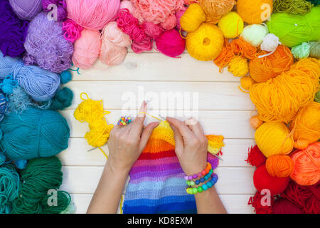 Kugeln aus farbigen Garnen. Blick von oben. alle Farben des Regenbogens. Probe gestrickt. Frauenhände gestrickt sind. häkeln. Stockfoto