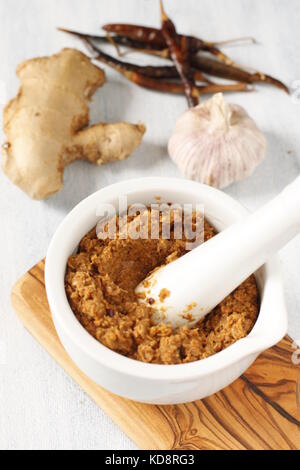 Currypaste auf einem weißen Mörtel mit Knoblauch, Chili und Ingwer Stockfoto