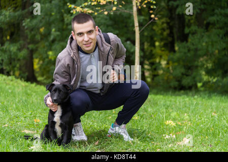 Mann mit schwarzer Hund auf dem Rasen im Park Stockfoto