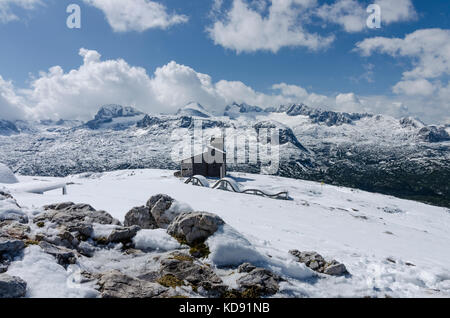 Verschneite Landschaft - der Blick auf den Dachstein Top vom Wanderweg mit einer Kapelle und einer Gruppe von Touristen zu Krippenstein Stockfoto