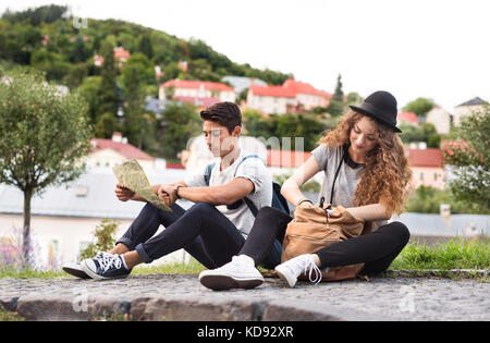 Zwei schöne junge Touristen mit Karte in der Altstadt. Teenager auf dem Boden sitzend. Stockfoto