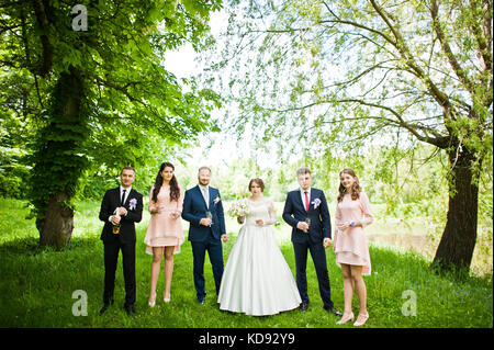 Hochzeit paar, Brautjungfern und groomsman Warten auf bester Mann, um eine Flasche Champagner in einer atemberaubenden Natur Ecke geöffnet. Stockfoto