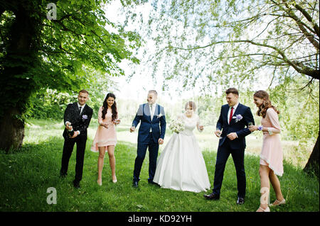 Hochzeit paar, Brautjungfern und groomsman Warten auf bester Mann, um eine Flasche Champagner in einer atemberaubenden Natur Ecke geöffnet. Stockfoto