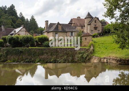 SEGUR-LE-CHATEAU, Frankreich - 30. JUNI 2017: Blick über den Fluss Auvezere zu einem malerischen mittelalterlichen Teil des Dorfes im Sommer Sonne läuft. Stockfoto