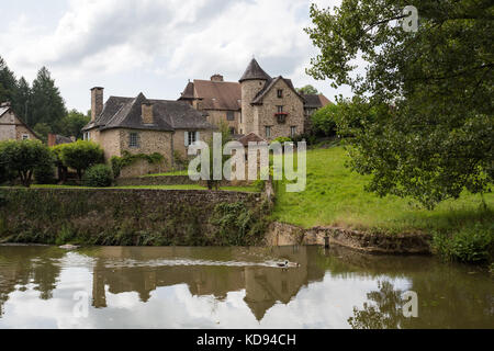 SEGUR-LE-CHATEAU, Frankreich - 30. JUNI 2017: Blick über den Fluss Auvezere, mit ein paar Enten, zu einem malerischen mittelalterlichen Teil des Dorfes in der Stockfoto