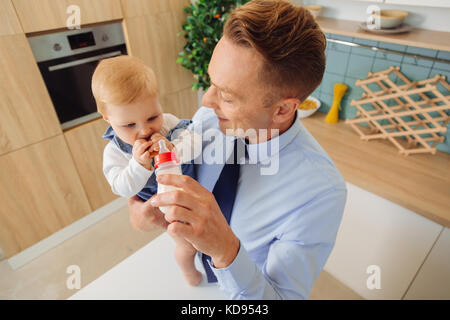 Gerne nette Mann, der eine Flasche mit Milch zu seiner Tochter Stockfoto