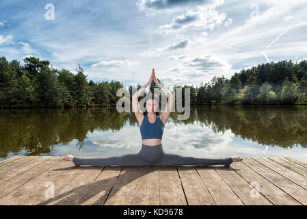 Frau vollen Splits auf einem Steg am Wasser Stockfoto