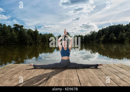 Frau vollen Splits auf einem Steg am Wasser Stockfoto