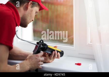 Arbeitnehmer Anwendung Silikondichtmittel unter Fensterrahmen Stockfoto