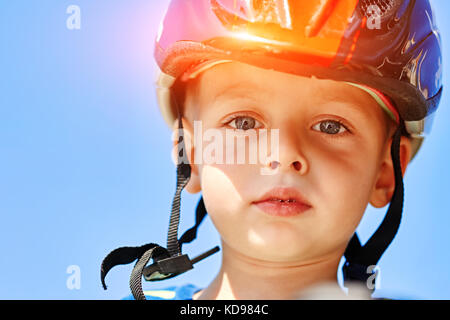 Kind mit einem Helm lacht glücklich am Park. closeup Stockfoto