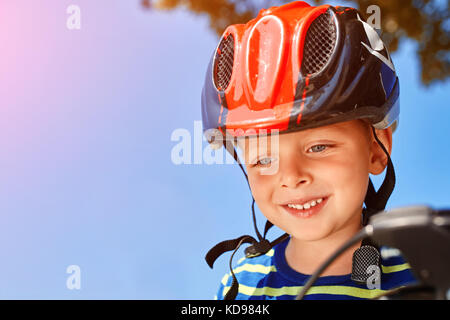 Kind mit einem Helm lacht glücklich am Park. closeup Stockfoto