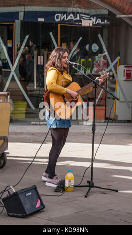 Eine junge weibliche Gaukler singen und Gitarre spielen in Stratford-upon-Avon, England, Großbritannien Stockfoto