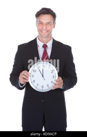 Portrait von lächelnden reife Geschäftsmann holding Wecker Stockfoto