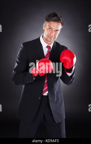 Reifen Geschäftsmann in Boxhandschuhe über schwarzen Hintergrund Stockfoto