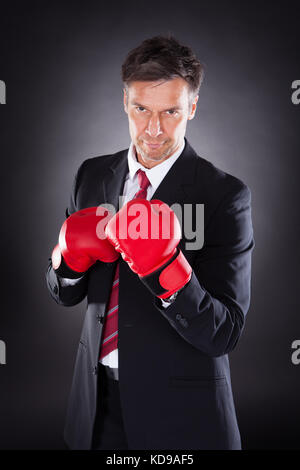 Reifen Geschäftsmann in Boxhandschuhe über schwarzen Hintergrund Stockfoto