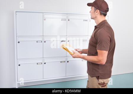 Porträt von Reifen Postboten Briefe ins Postfach Stockfoto