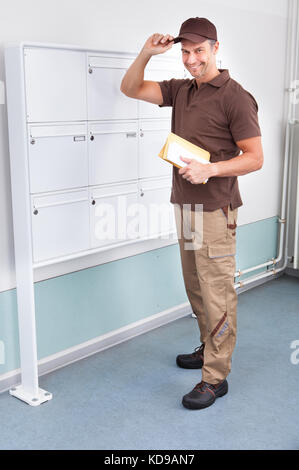 Porträt von zuversichtlich Postman hält seine Mütze Stockfoto