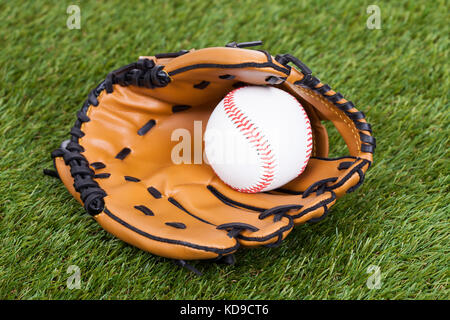Leder-Handschuh mit Baseball Ball auf grünem Rasen Stockfoto