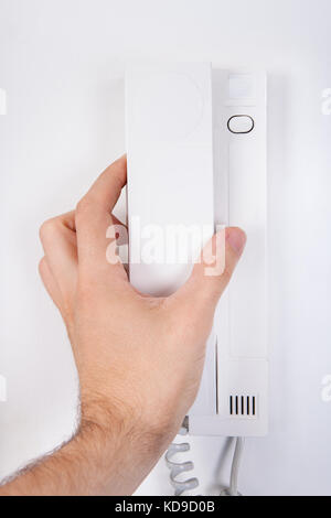 Hand, die Empfänger auf weiße Wand befestigt Stockfoto