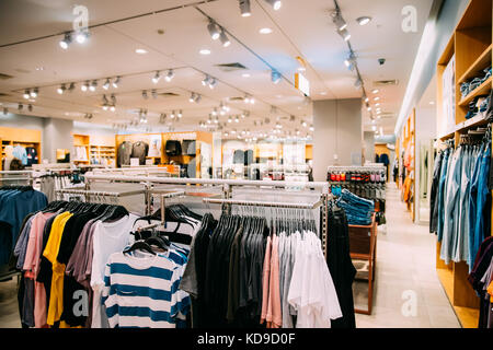 Bunte helle Kleidung in den Regalen und Kleiderbügel im Store im Einkaufszentrum. Stockfoto