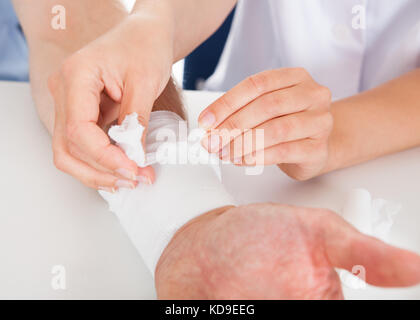 In der Nähe der weiblichen Arzt bandagieren Patienten Handgelenk Stockfoto