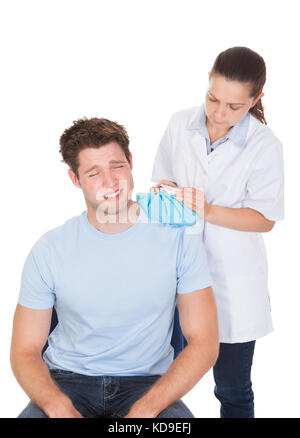 Arzt, der die Behandlung von Patienten mit icepack auf weißem Hintergrund Stockfoto