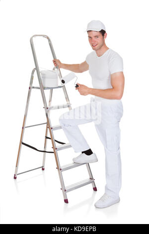 Gerne Maler mit Paint Bucket und Walze auf Leiter Stockfoto