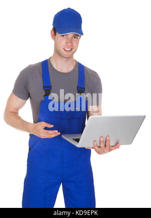 Portrait von Happy Mechaniker holding Laptop auf weißem Hintergrund Stockfoto