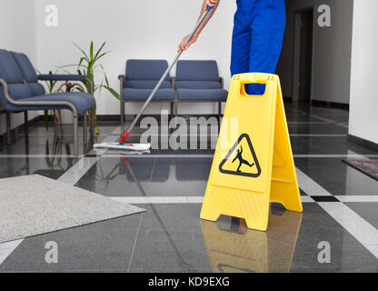 Der Mann in der Nähe der Reinigung Den Boden mit gelben nassen Boden Zeichen Stockfoto