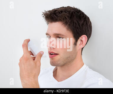 Junger Mann hält ein Inhaliergerät für Medizin Stockfoto
