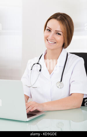 Porträt der glückliche junge Ärztin Arbeiten am Laptop Stockfoto