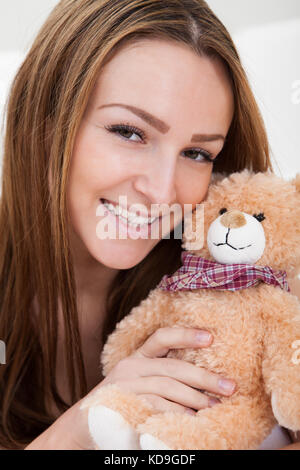 Junge schöne Frau schlafend auf dem Bett mit ihrem Teddybär Stockfoto