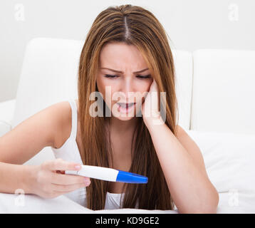 Junge Frau Kontrolle der Schwangerschaft Test zu Hause besorgt Stockfoto