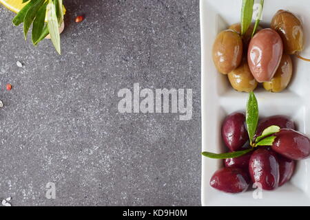 Platte der schwarze und grüne Oliven auf einem grauen Abstrakt Hintergrund mit der Kopie Raum. gesunde Ernährung Konzept Stockfoto