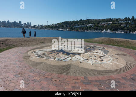 Touristen am sculpted analemmatic Sonnenuhr auf Drachenfliegen Hill; Seattle skyline über Lake Union, Gas funktioniert Park, Seattle, Washington Stockfoto