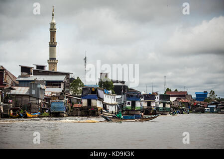 Einzigartige Boote am Ufer des Flusses Mahakam in Kalimantan. Borneo River Transport. Blick vom Fluss in der Dritten Welt Strukturen, Minarett und ungewöhnliche Boote Stockfoto