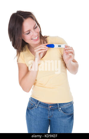 Porträt von Happy Woman Looking At Schwangerschaft Ergebnis Over White Background Stockfoto