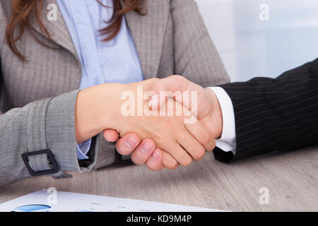 Nahaufnahme der Geschäftsleute, die zitternden Händen im Büro Schreibtisch Stockfoto