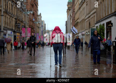 Mädchen mit Gehstöcken auf der Buchanan Street Glasgow in Perspektive von hinter Krücken Gehhilfen Stockfoto