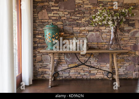 Wohnzimmer mit dekorativen Tisch, stein Wand hinter. Stockfoto