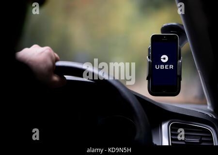 Ein kaukasischer Mann, dessen Gesicht verdunkelt ist ein Uber fährt Taxi, und hat das Firmenlogo auf seinem Smartphone, die an der Windschutzscheibe befestigt ist. Stockfoto