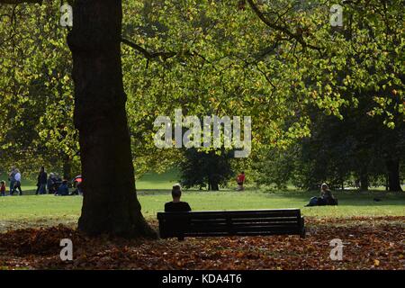 London, Großbritannien. 12 Okt, 2017. UK Wetter. Eine Frau genießt den Herbst Sonnenschein im Green Park Credit: Patricia Phillips/Alamy leben Nachrichten Stockfoto