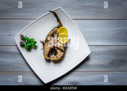 Gegrillten yellowtail Bernsteinmakrele mit Zitronenscheiben auf Holz- Hintergrund. Stockfoto