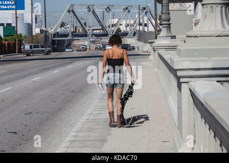 Obdachlose Frau geht über die Washington Boulevard Bridge in der Nähe der Innenstadt von Los Angeles, Kalifornien, USA Stockfoto