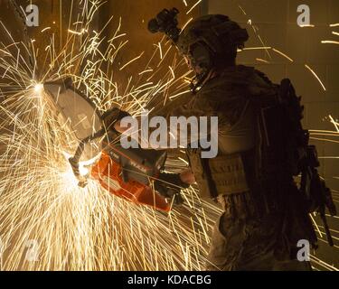 Ein Soldat des US Marine Corps verwendet eine sah durch eine Metalltür während der Marine spezielle Betrieb Schule master breacher Kurs auf der Marine Corps Base Camp Lejeune Stein bay August 20, 2015 in Jacksonville, North Carolina. Stockfoto