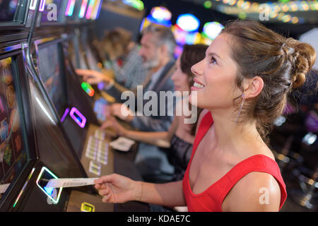 Junge schöne Frau spielen der Slot Maschine Stockfoto