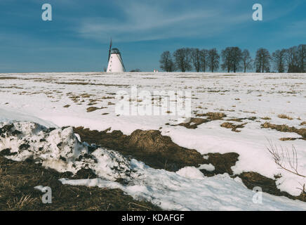 Alte Windmühle stehend im Winter die schneebedeckten Feld gegen den blauen Himmel Stockfoto