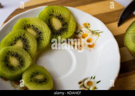 Kiwi Slices auf einer weißen Platte, Holz- Board Stockfoto