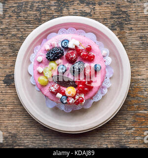 Süße Käsekuchen mit frischen Beeren und Joghurt Creme. Lecker Himbeeren Kuchen mit frischen Erdbeeren, Himbeeren, Heidelbeeren, Johannisbeeren und Blackberry Früchte auf rustikalen Holzmöbeln Hintergrund. Stockfoto